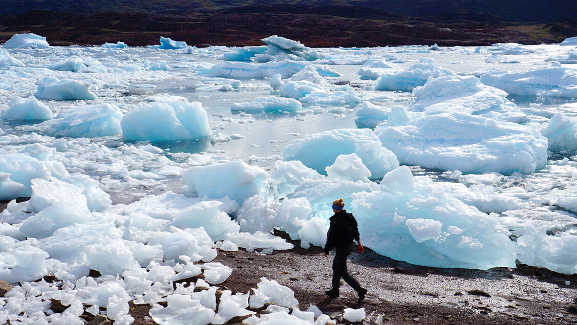 Person går mellem strandede stykker af isbjerge