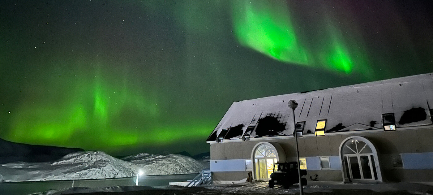 Hotel Diskobay med stjerner og nordlys på himlen.