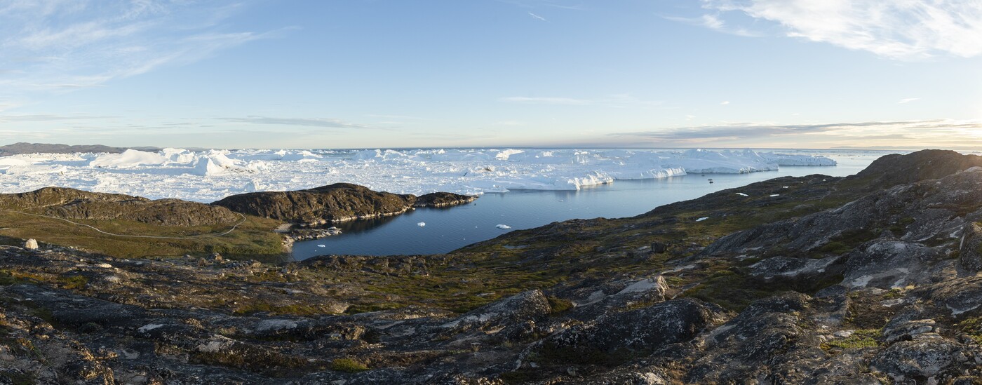 Udsigt over isfjorden fra Sermermiut, med isbjerge og blå himmel. 