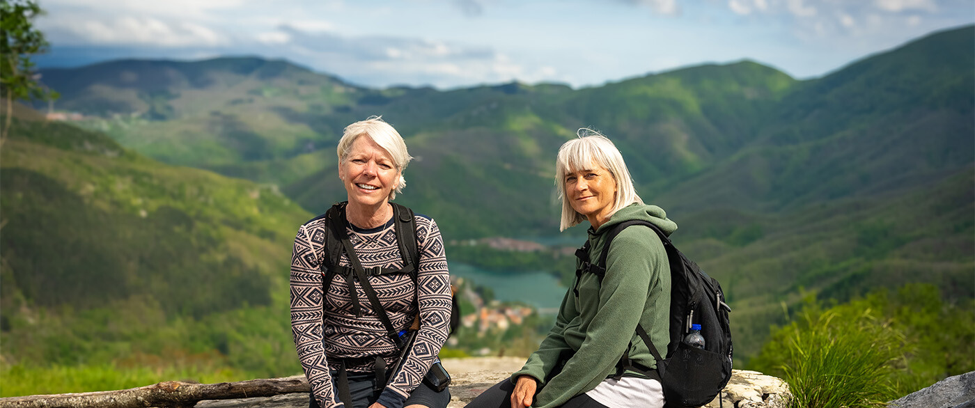 To kvinder poserer foran udsigt over bjerge og dal.