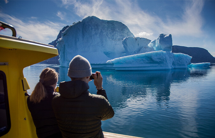 Two people taking picture of the beautiful view of ice frjord.