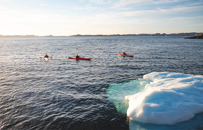 3 people on each kayak in the ocean.