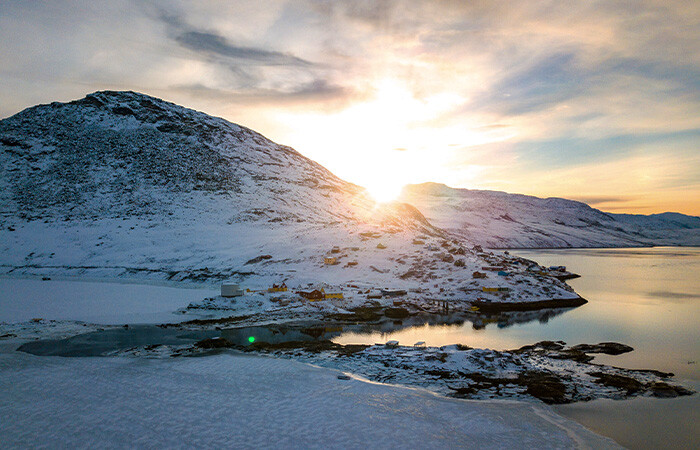 Smuk udsigt til Kapisillit i vinter, fyldt med sne og sol i baggrunden.