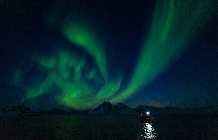 Nordlys over vand og fjelder.