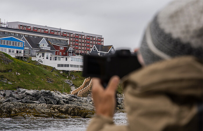 A person taking pictures of the view of the city, with grey sky in the background.