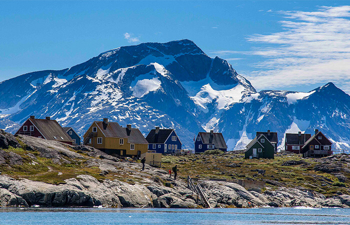 Flotte huse i byen ved vandet, med klar blå himmel og vand.