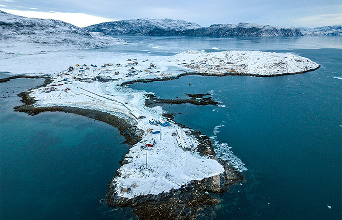 Stunning view of the island covered in snow, with blue sky and ocean.