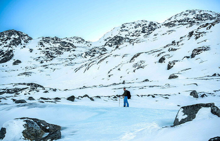 A man hiking on untouched snow with beautiful blue sky in the background.